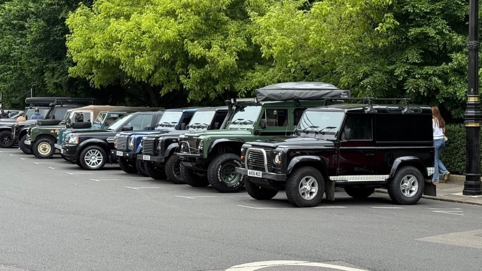 A row of mud-marked Land Rover Defenders parked nose-in beside the railings of Belgrave Square.
