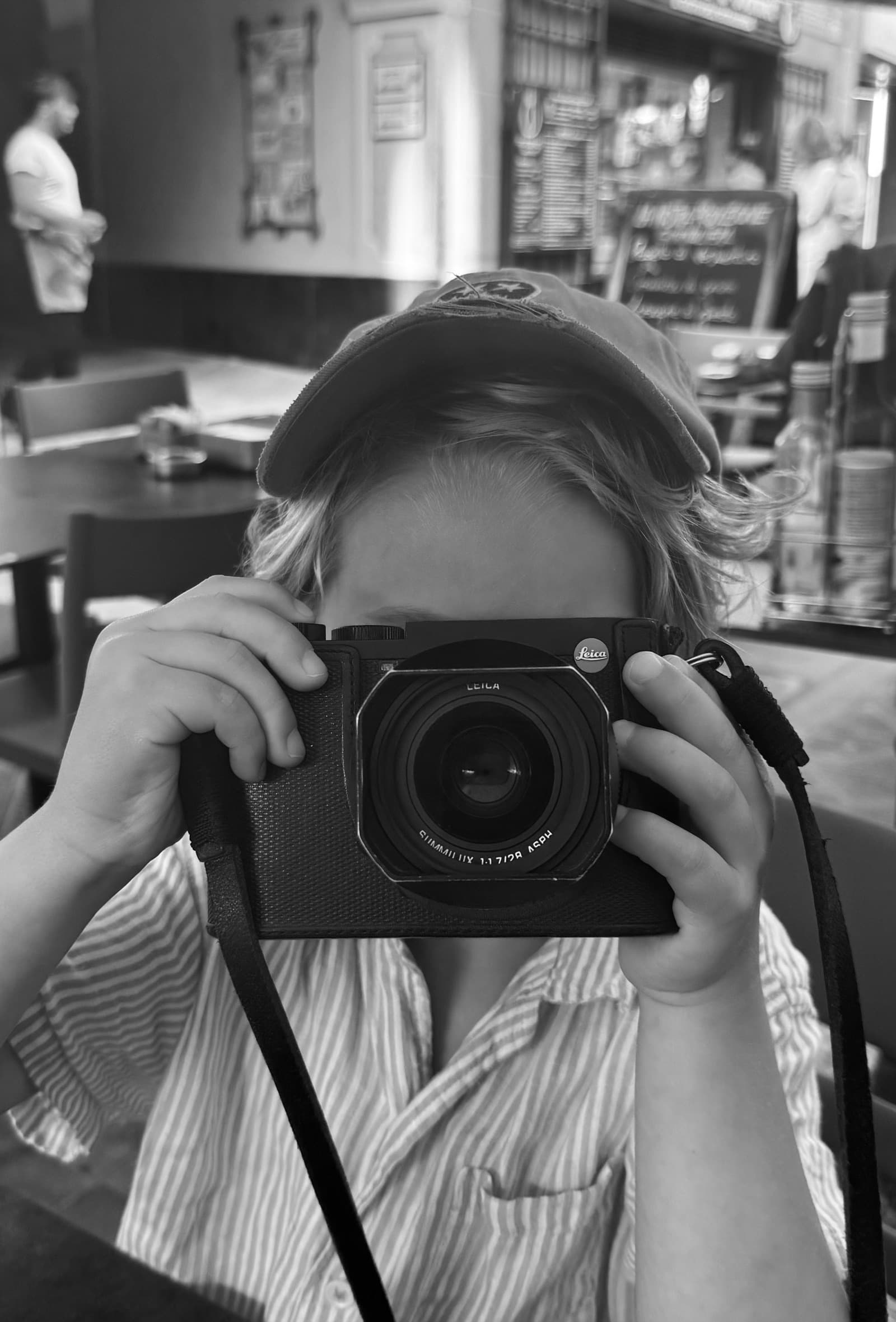 A well-used black Leica Q2 handed across a café table.