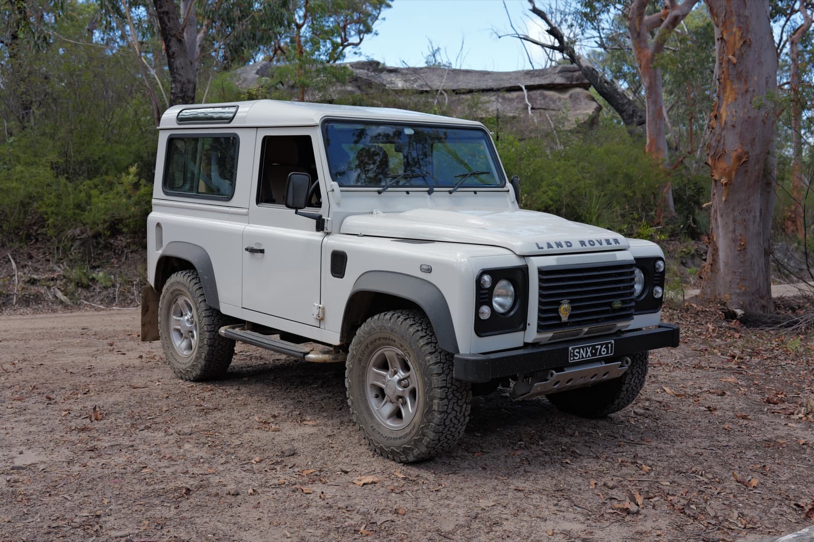 A white Land Rover Defender 90 parked outside after use.